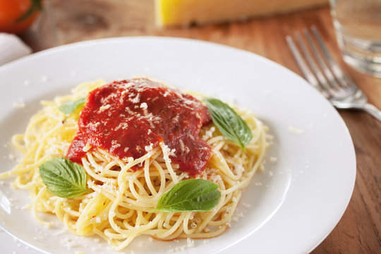 spaghetti with tomato sauce in plate on wooden board