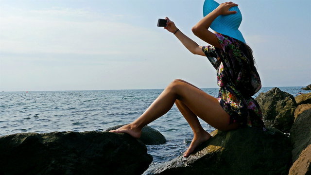 Young woman sitting on the rocky sea shore