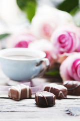 Pink roses, coffe and chocolate on the wooden table
