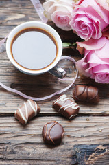 Pink roses, coffe and chocolate on the wooden table