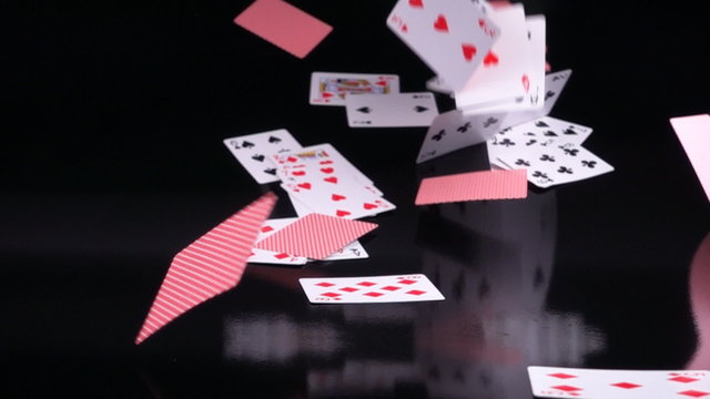 Playing cards falling on black background in slow motion.