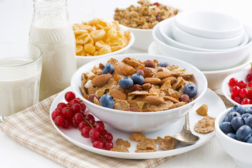 breakfast with cereals flakes, nuts and berries on table