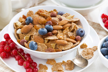 breakfast with cereals flakes, nuts and berries, closeup