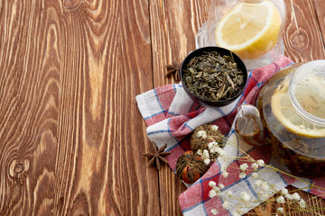Ripe lemon, cinnamon and fruit drink in glass teapot on wooden background