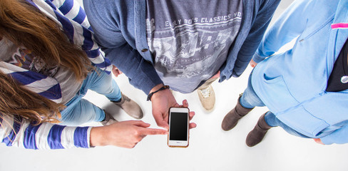 Eine Gruppe steht um ein Handy / Tablet 