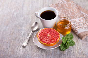 Baked grapefruit with honey and a cup of black coffee for breakfast, selective focus 