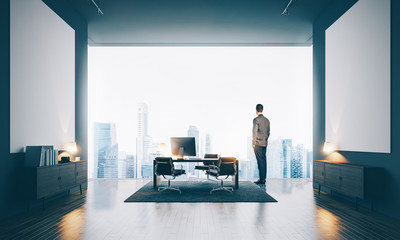Businessman wearing modern suit and looking at the city in contemporary office. Horizontal