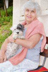 beautiful Senior smiling woman hugging her small white poodle dog in the mountain