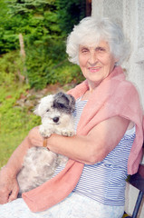 beautiful Senior smiling woman hugging her small white poodle dog in the mountain