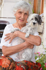 beautiful Senior smiling woman hugging her small white poodle dog in the mountain