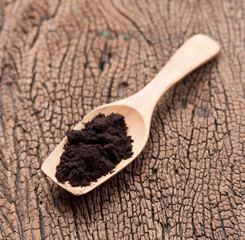 close up of a spoon and black powder on wood