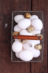 chicken and quail eggs with feathers in a metal basket