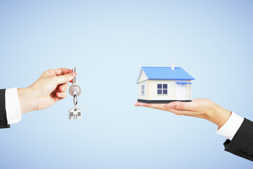 Real estate concept with man hand with key and house in another