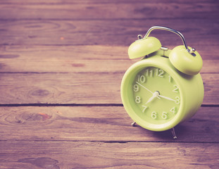 Green alarm clock on wood,vintage color toned image