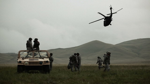 Shot of soldiers in Humvee while Black Hawk helicopter flies overhead.