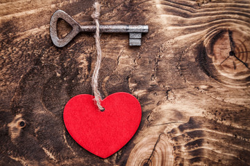 Love concept. Old key and a heart on wooden background