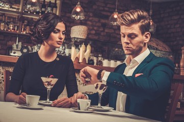Stylish wealthy couple having desert and coffee together in a restaurant.