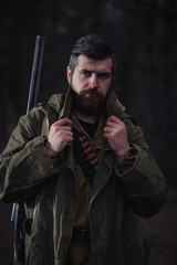 brutal hunter, bearded man in warm hat with a gun in his hand