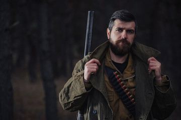 brutal hunter, bearded man in warm hat with a gun in his hand