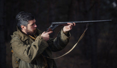 brutal hunter, bearded man in warm hat with a gun in his hand
