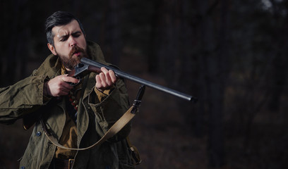 brutal hunter, bearded man in warm hat with a gun in his hand