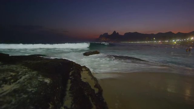Slow motion tracking shot of the ocean flowing in against the Arpoador Rocks