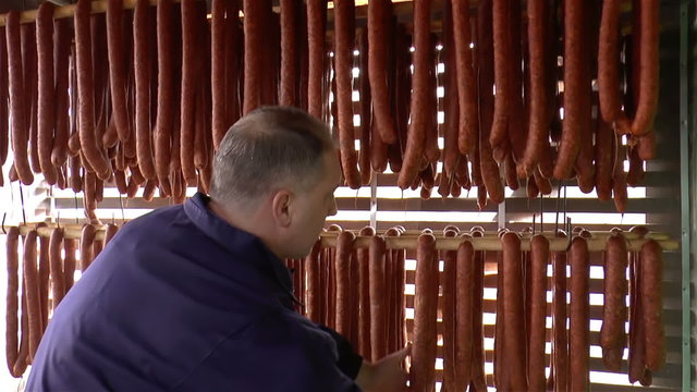 Worker checks smoked dry sausages.
