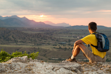 Naklejka premium Hiker with backpack sitting on a rock