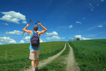 Wanderer auf dem Feldweg, Nordic Walking über grüne Landschaft