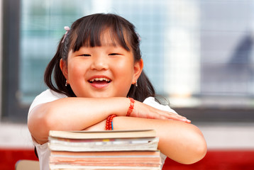 Happy chinese girl at primary school holding her books