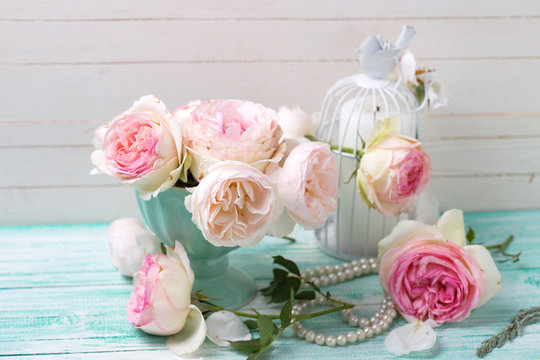 Pink roses and candle on turquoise painted wooden planks