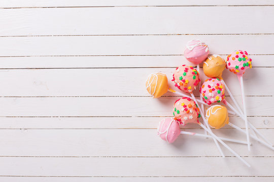 Cake pops on white  painted wooden background.
