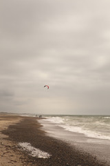 The Beach South of Klitmoller. A long straight beach, south of the town of Klitmoller, is where the kite surfers gather. A colourful kite brightens up an otherwise very stormy sky.