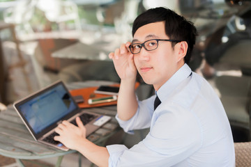 Fototapeta premium Young Asian businessman working on laptop in outdoor workplace