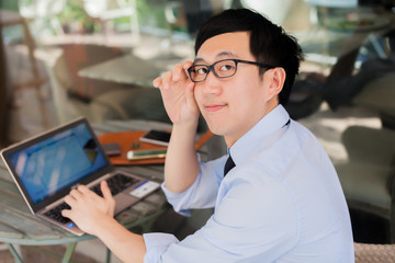 Young Asian businessman working on laptop in outdoor workplace