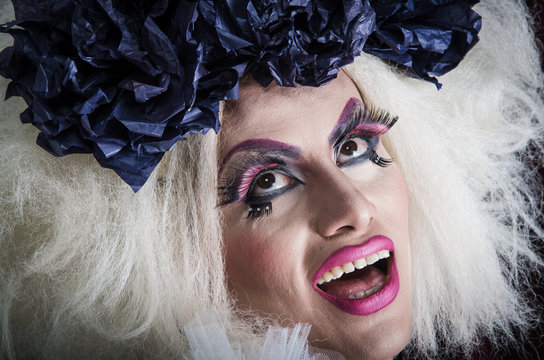 Drag queen with spectacular makeup, glamorous trashy look, posing happily and charming camera from sideways angle