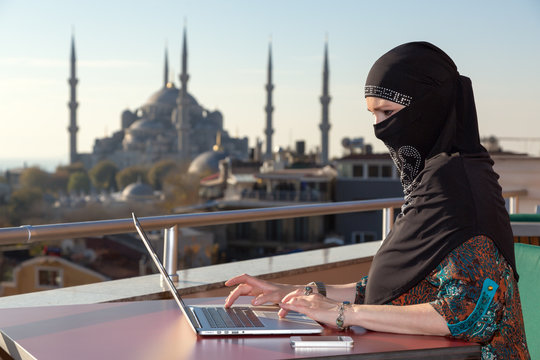 Traditionally dressed Muslim Woman working on computer