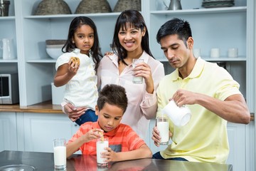 Happy family eating biscuits and drinking milk