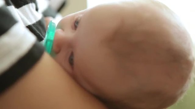 A close up shot of a young man rocking a beautiful baby in his arms.