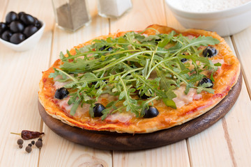 Homemade pizza with bacon, olives and arugula
