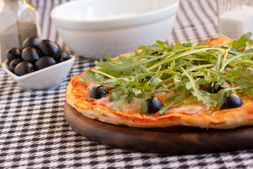 Homemade pizza with bacon, olives and arugula