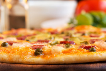 Homemade pizza with hunter sausages, bacon, peas and pickled cucumbers