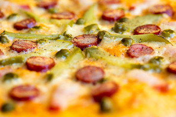 Homemade pizza with hunter sausages, bacon, peas and pickled cucumbers