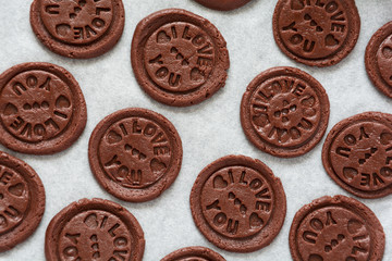 Preparing chocolate cookies with pressed text 'I love you'