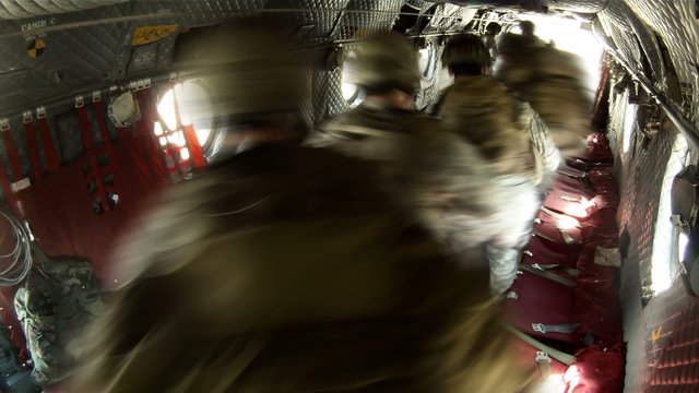 Chinook helicopter as it lands and soldiers stand up and move out, weapons in hand.