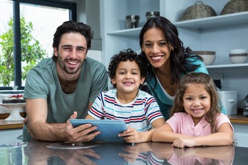 Smiling family using tablet in the kitchen