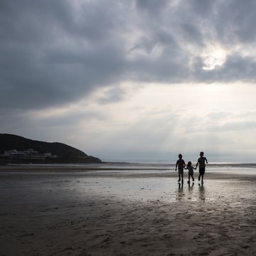 Silhouette of three children holding hand running on beach