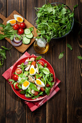 Fresh salad with chicken, tomatoes, eggs and arugula on plate