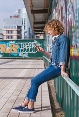 Young curly woman with earphones in sunny day