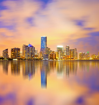 Miami Florida, sunset cityscape over the city panoramic skyline with lights on the modern downtown skyscraper buildings and Biscayne Bay water reflection
